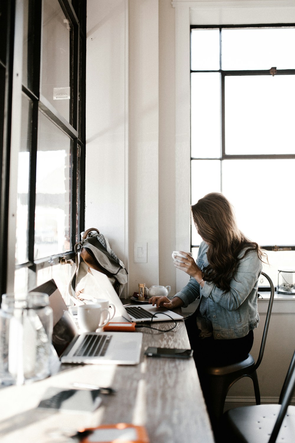 A woman working on a laptop at a café table, with a coffee beside her.